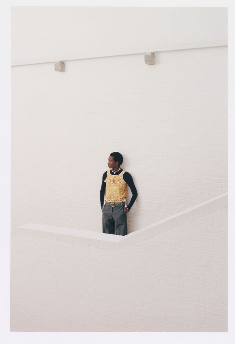 Model wearing a yellow patterned top and dark trousers standing against a white wall for Eurowoman