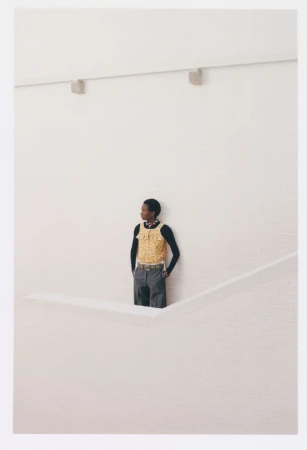 Model wearing a yellow patterned top and dark trousers standing against a white wall for Eurowoman