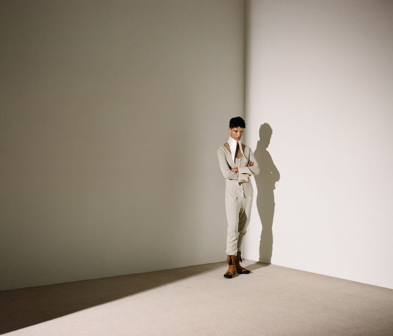 Model Georgia Palmer standing in a minimalist room corner wearing a cream outfit with oversized collar and boots.