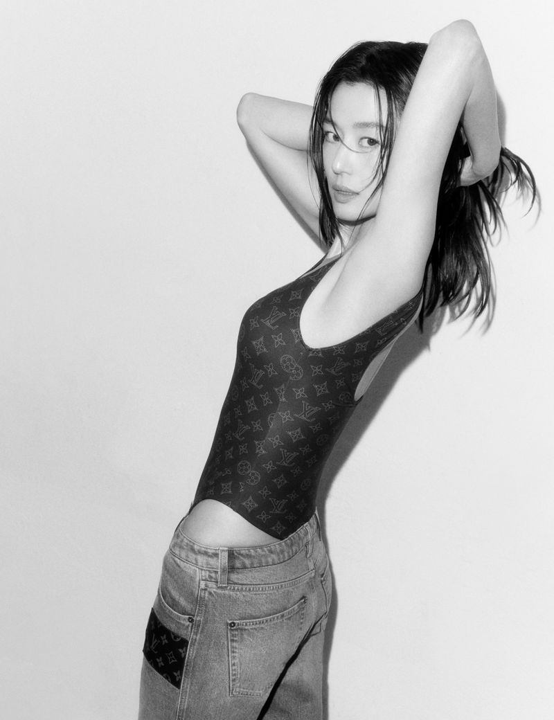 Jun Ji-hyun posing in a monogram bodysuit and denim jeans against a plain studio background.