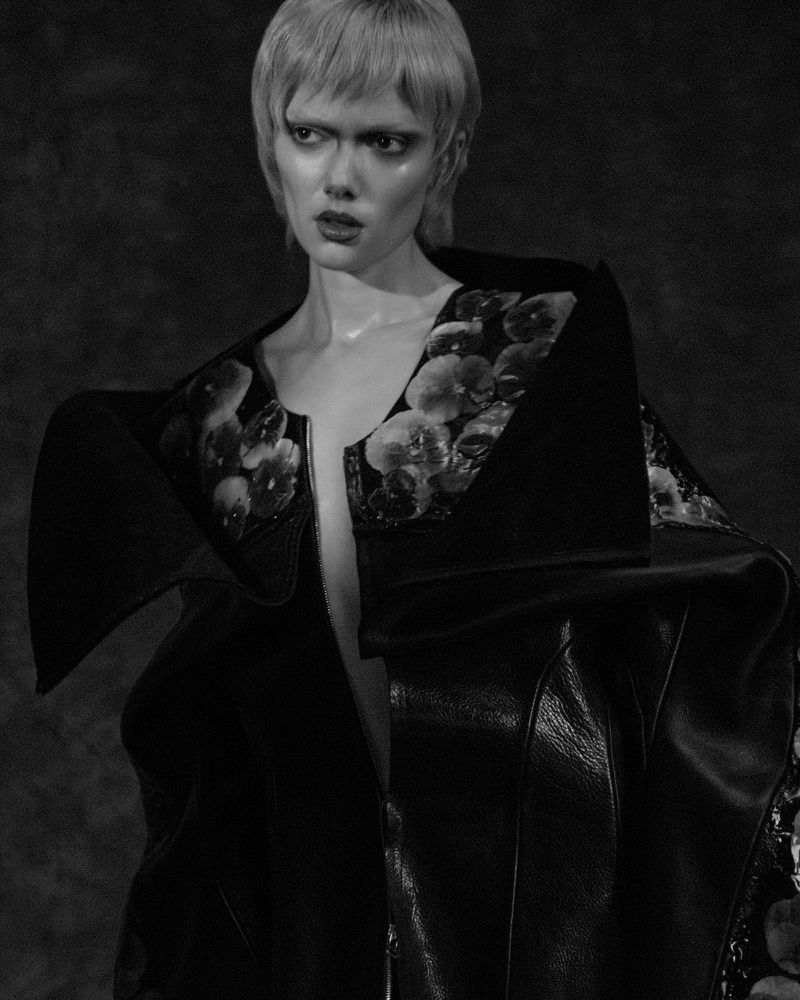 Puck Loomans in an oversized black jacket with sculpted floral lapels in a monochrome editorial portrait for Glamcult Magazine.