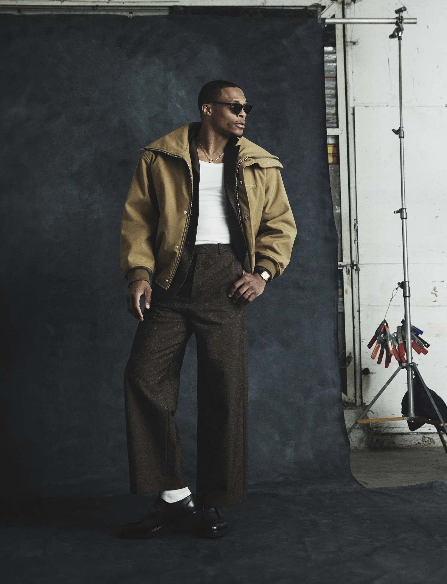 Russell Westbrook wearing a camel jacket and sunglasses against a dark textured backdrop in Numero Netherlands