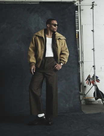 Russell Westbrook wearing a camel jacket and sunglasses against a dark textured backdrop in Numero Netherlands