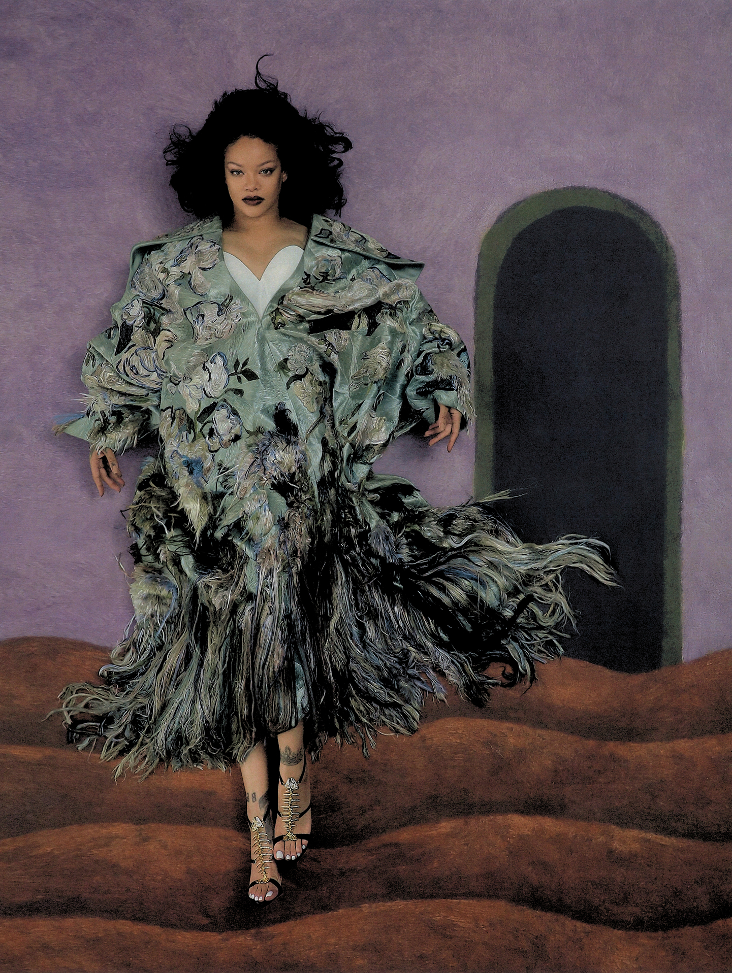 Full-length portrait of Rihanna wearing a textured floral coat against a purple textured wall with an arched doorway.
