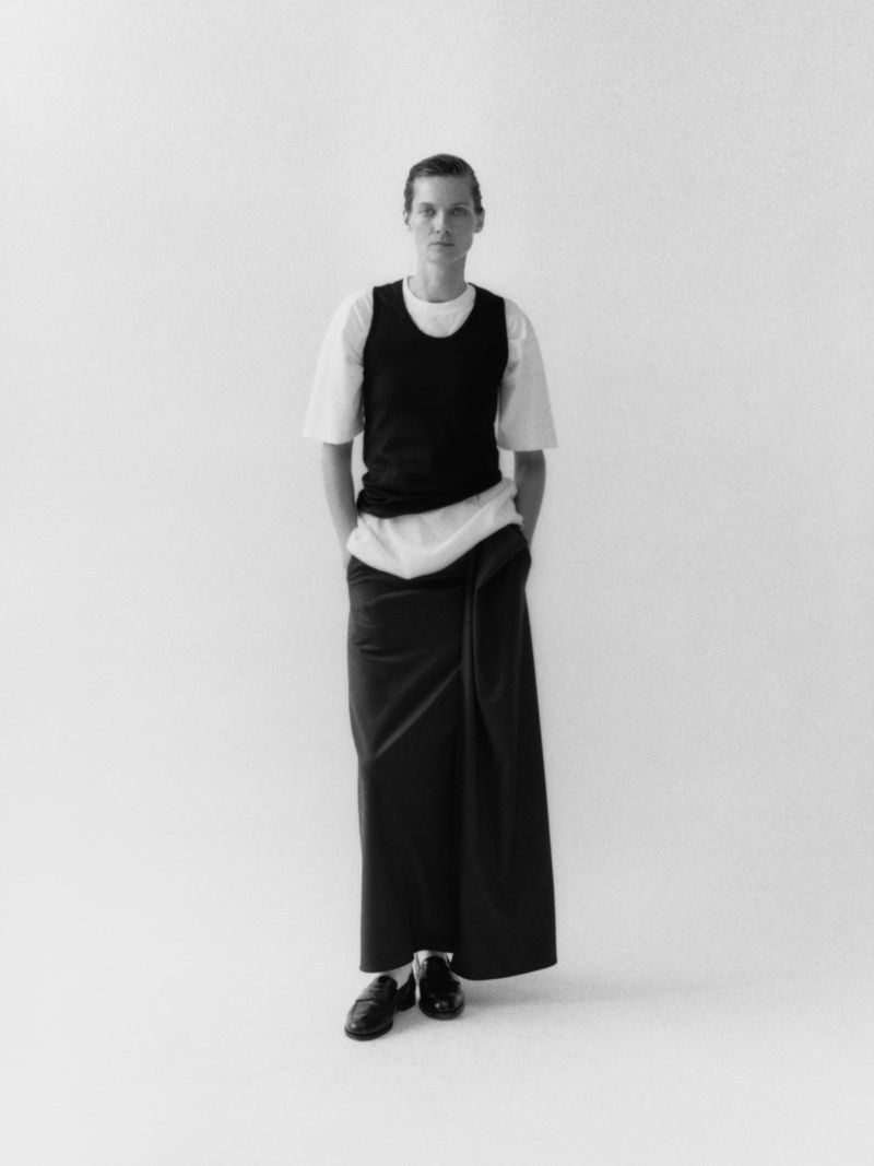 Model Karolin Wolter wearing layered dark vest and white t-shirt against a plain white studio background for ssstein AW27 campaign.