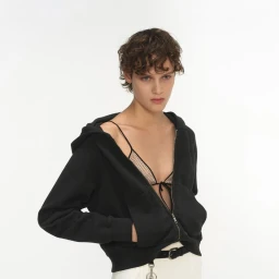 Model in a black zip-up hoodie and mesh triangle top against a white studio background for Prada Summer 2025.