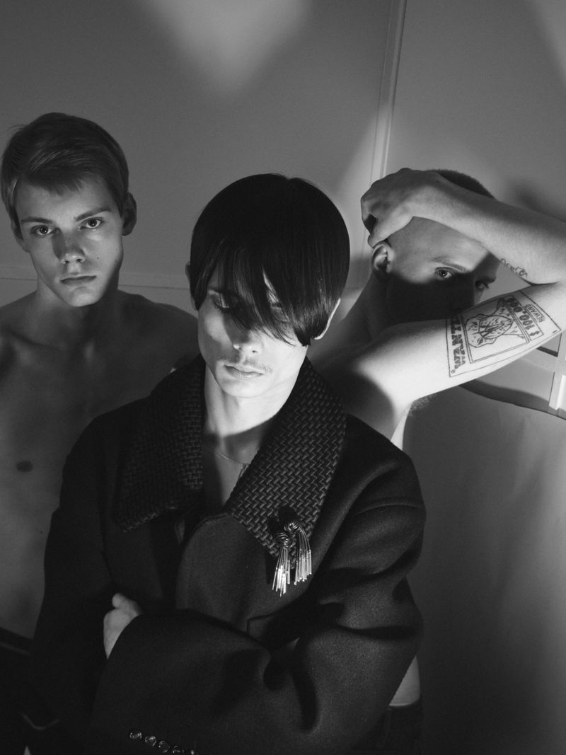 Monochrome portrait of three male models posing closely together, lit with dramatic high-contrast lighting for U Repubblica.