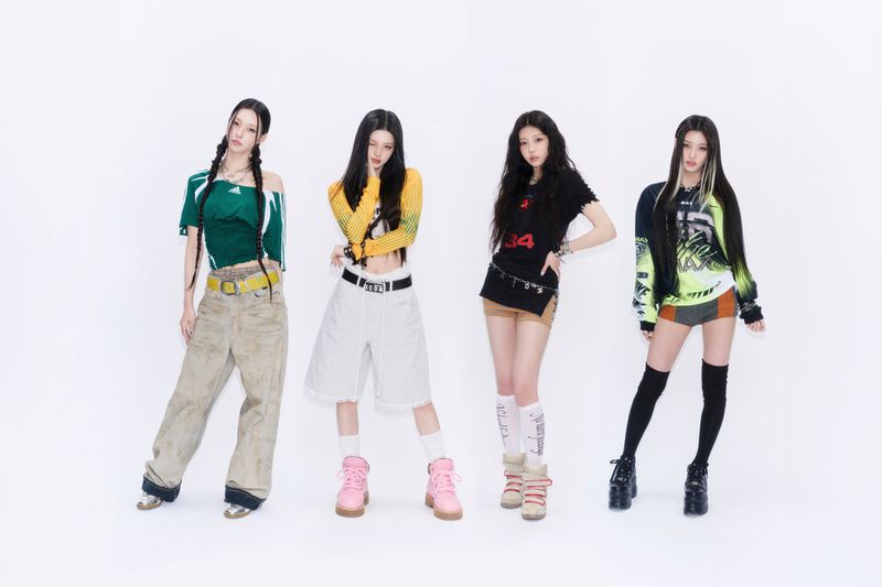 Four young women posing in eclectic Y2K streetwear and colorful outfits against a solid white studio background.