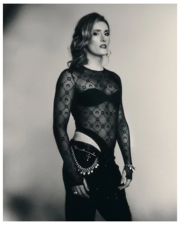 Monochrome portrait of Hannah Einbinder wearing a sheer patterned bodysuit and black trousers with beaded hip detailing.