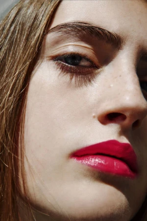 Close up beauty portrait of a model featuring bright magenta lipstick, winged eyeliner, and strong natural eyebrows.