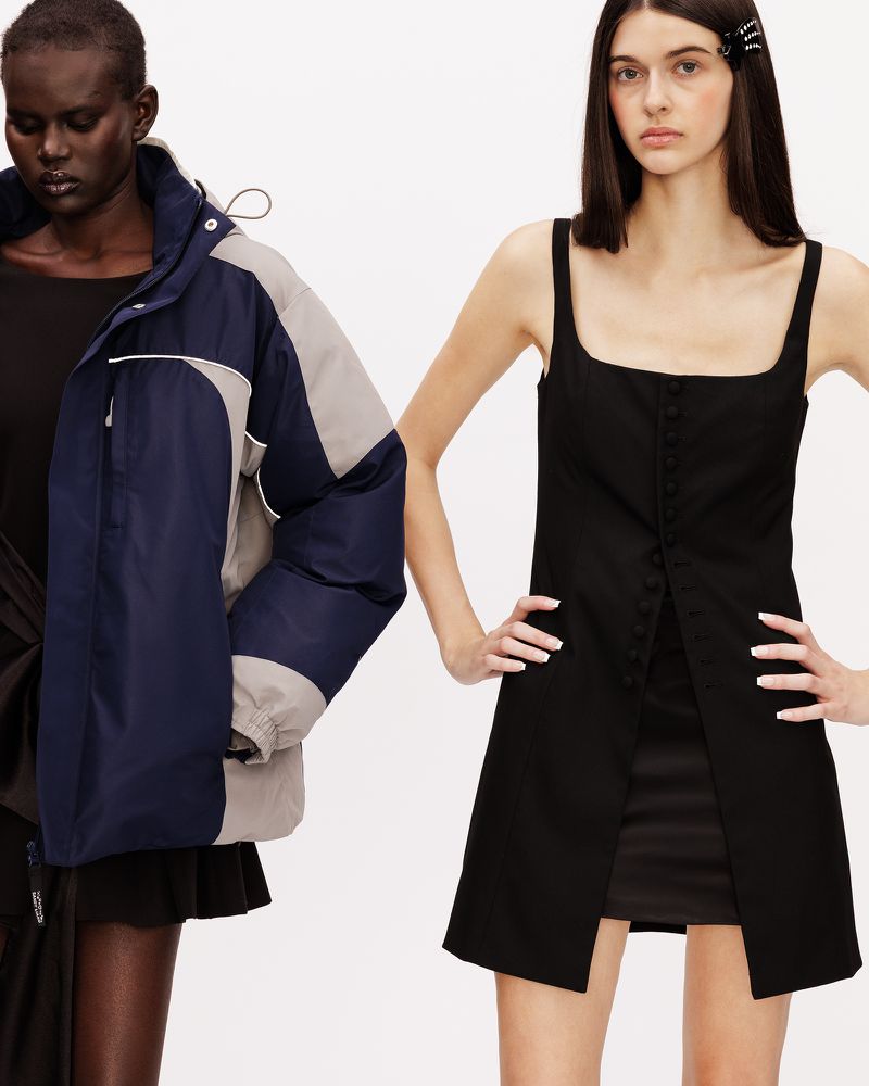 Two models posing against a white backdrop, one in an oversized navy jacket and one in a black square-neck mini dress.