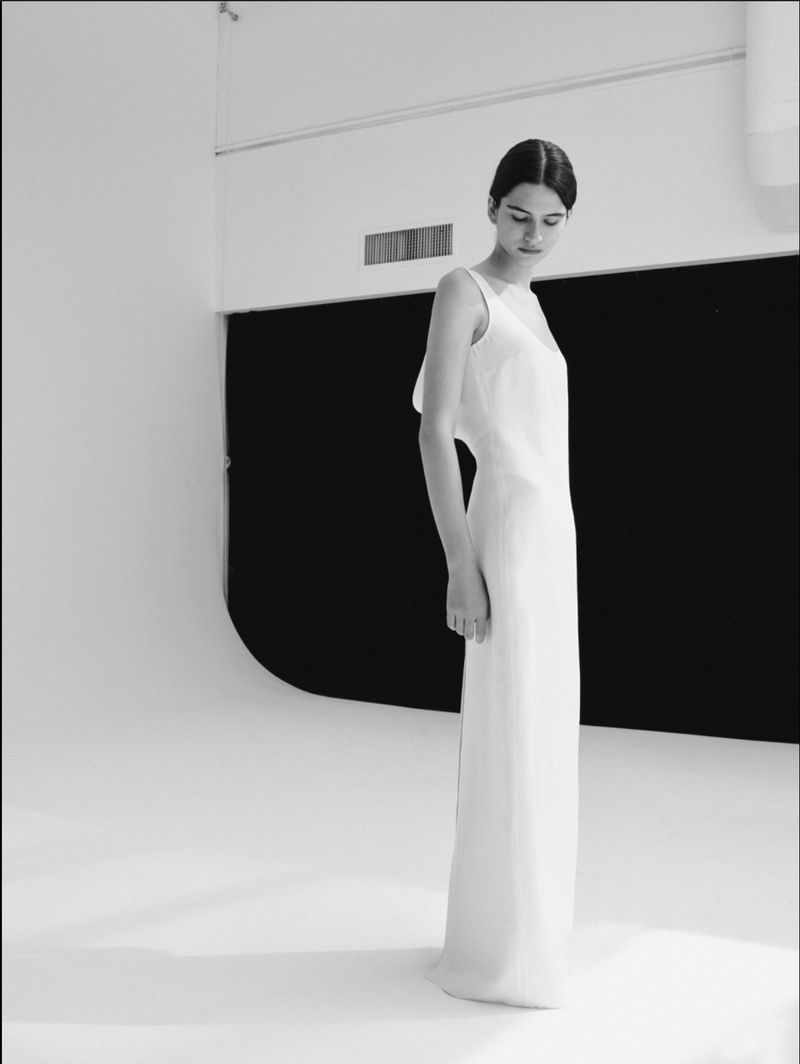 Model Peyton Cole standing in a sleeveless white maxi dress on a studio cyclorama for Heirlome Resort 2027.