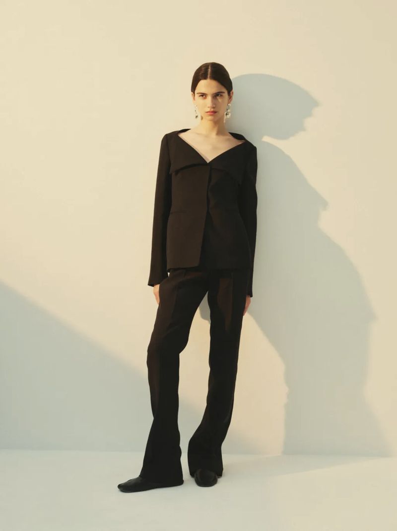 Model Peyton Cole poses in a structured black suit against a pale backdrop with a directional shadow for the Heirlome lookbook.