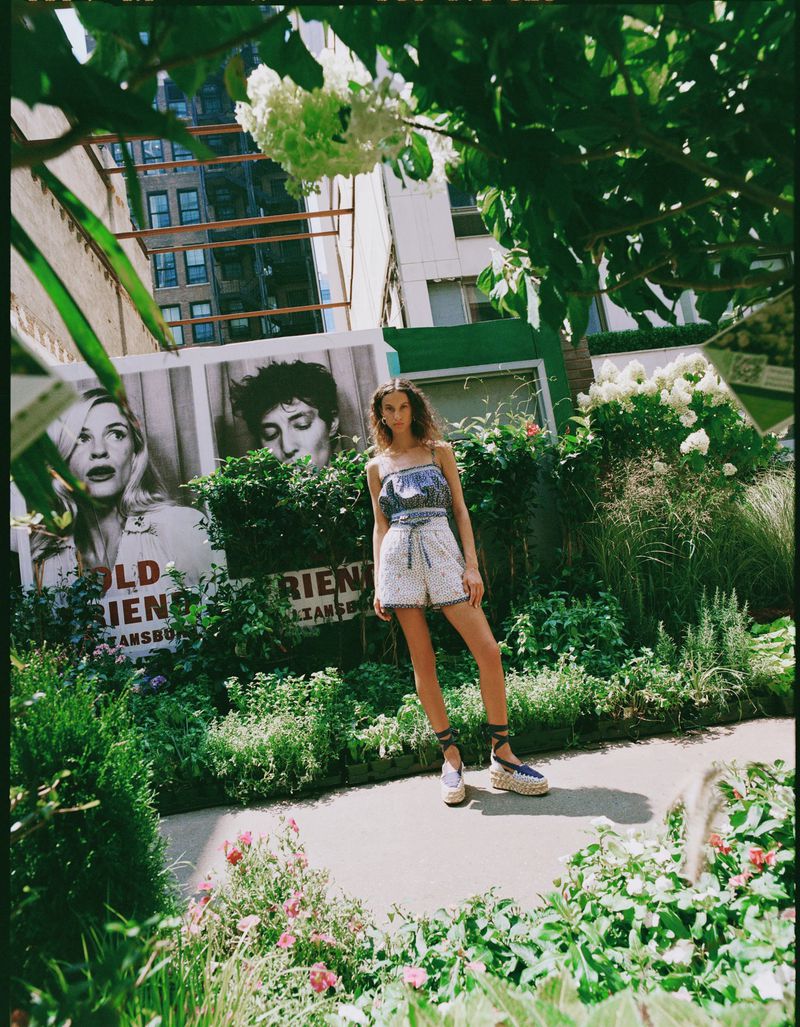 Model standing outdoors in a garden wearing patterned shorts and a strappy top for Loeffler Randall Spring 2026 Lookbook