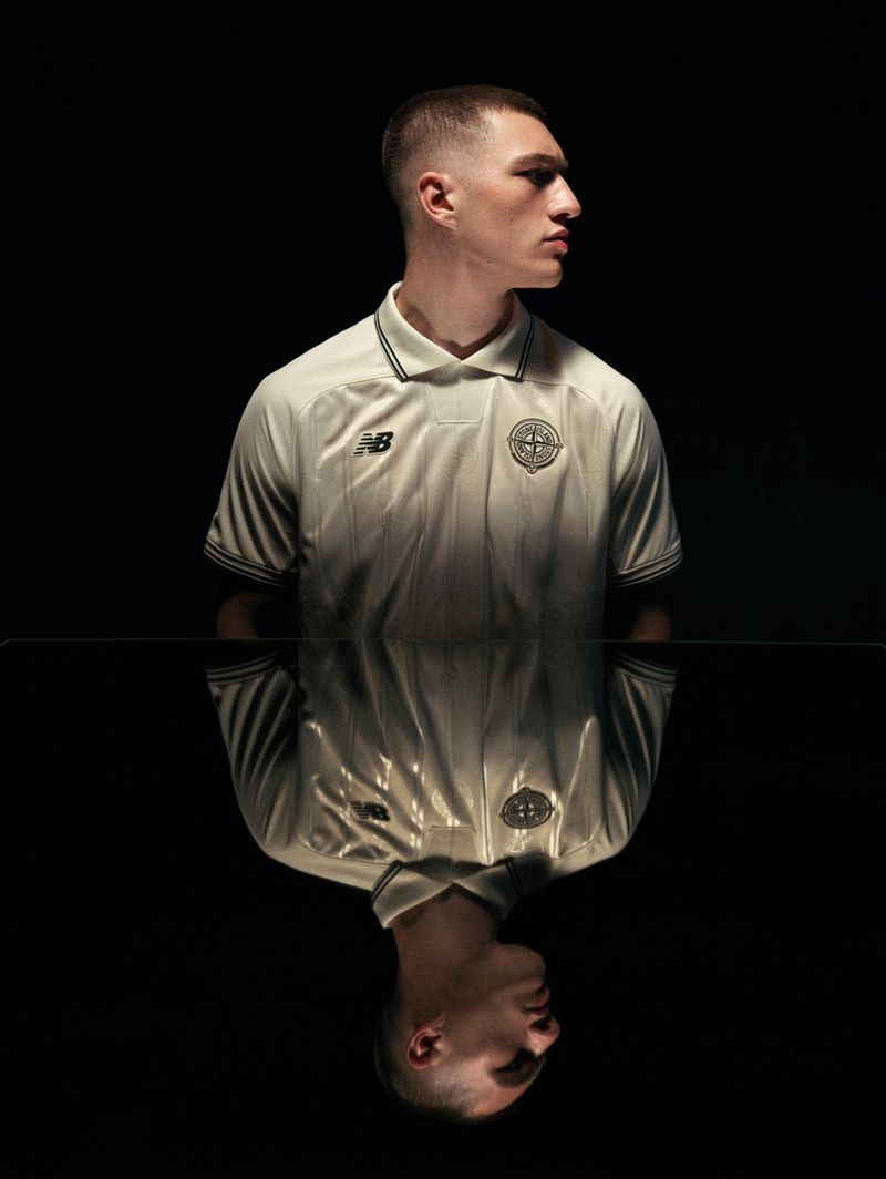Model in an off-white athletic polo jersey posing above a reflective black surface against a dark studio background.