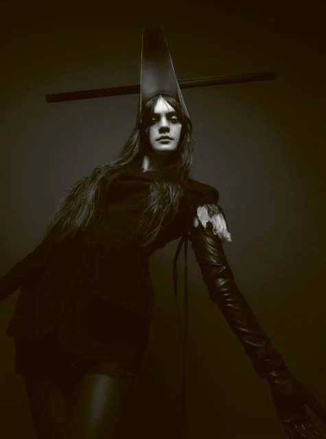 Fashionable person with long hair wearing a dramatic headpiece and gloves in a studio shot, dark lighting.
