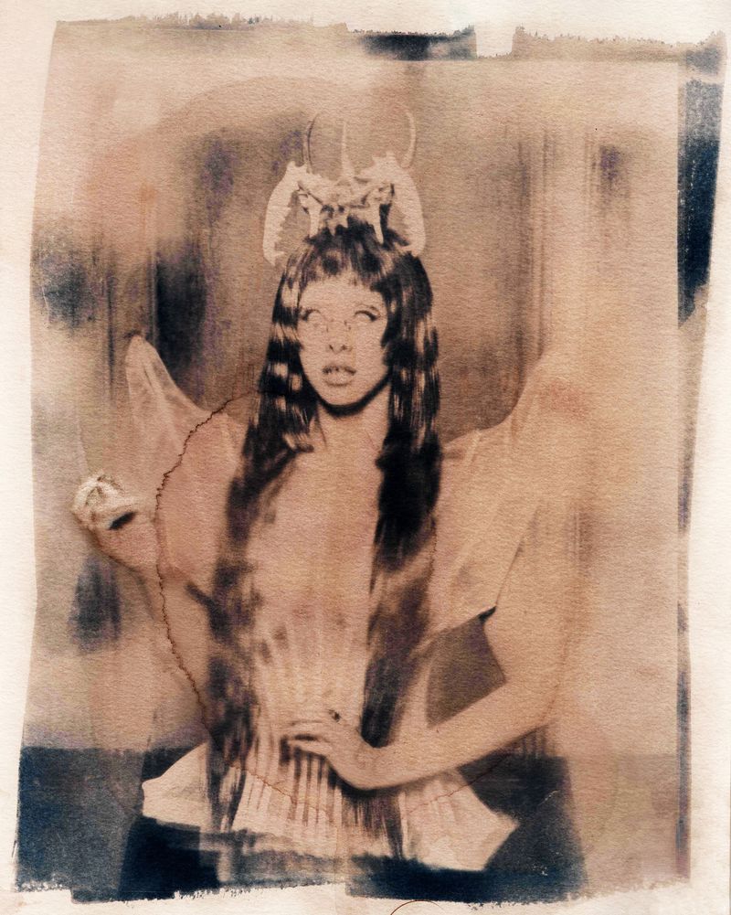 Melanie Martinez with sculptural headpiece and sheer winged outfit in a textured vintage print for 1883 Magazine.