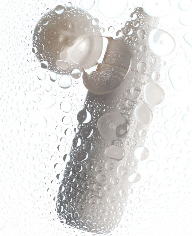 Image showcasing a white cleansing device partially covered in water droplets against a bright white background, emphasizing hygiene.