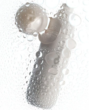 Image showcasing a white cleansing device partially covered in water droplets against a bright white background, emphasizing hygiene.