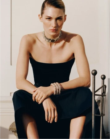 Grace Elizabeth seated wearing a strapless black dress with a statement choker necklace in direct sunlight.