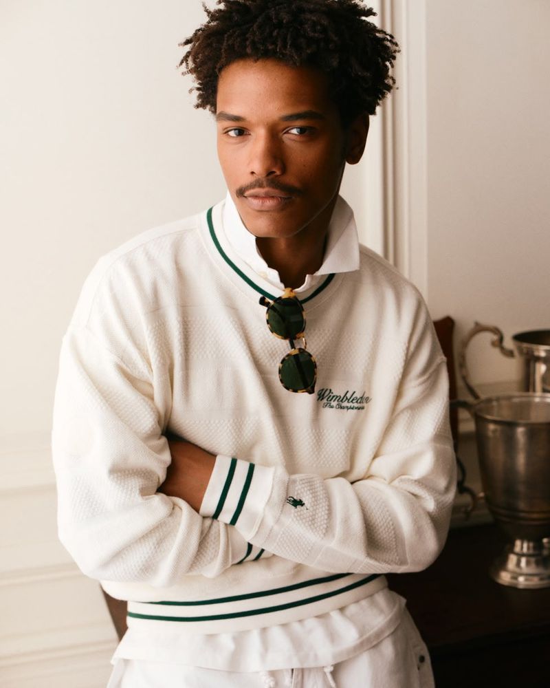 Nile Winchester wearing a white Polo Ralph Lauren Wimbledon sweatshirt with green striped trim and sunglasses hooked at the collar.