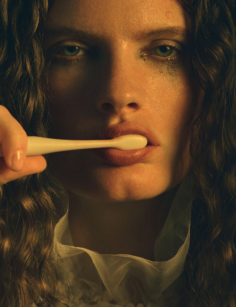 Model Carolina Burgin holds a white toothbrush to her mouth in a close-up beauty portrait for Vogue Scandinavia.