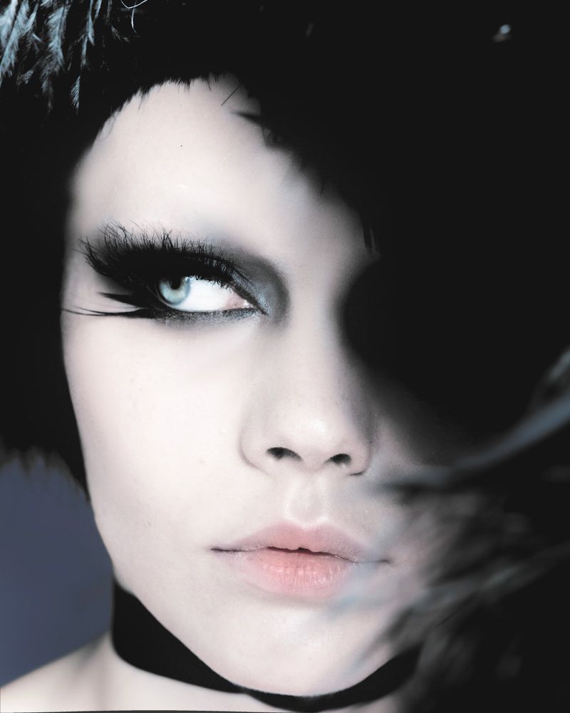 Close-up beauty portrait of a woman with dramatic exaggerated black eyelashes, smoky eyeshadow, and a black choker.