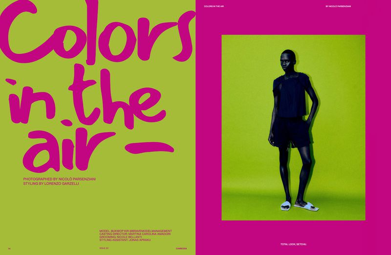 Magazine spread featuring a model in dark clothing against a bright green background with large pink typography.