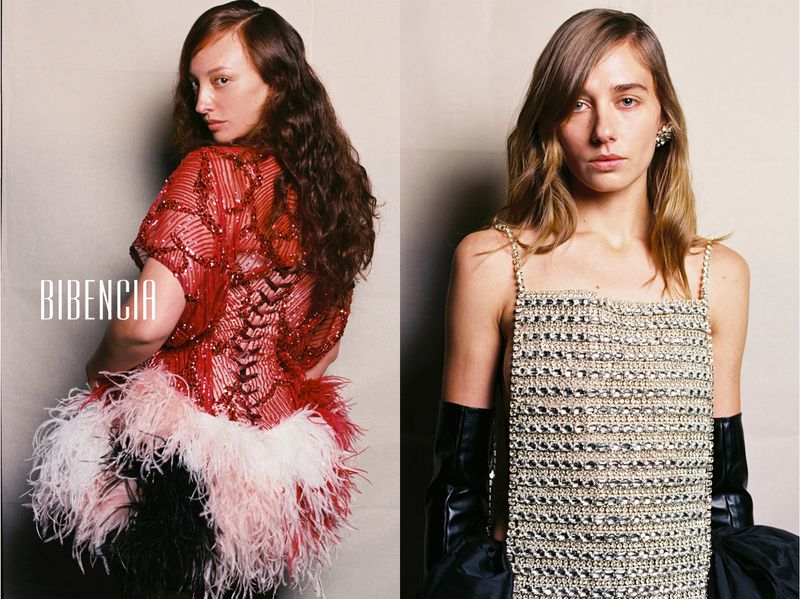 Two fashion models posing side by side wearing an embellished red feathered top and a crystal grid bib with black opera gloves.