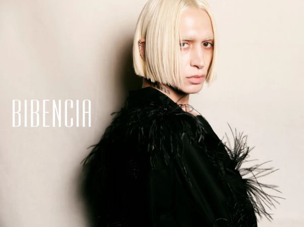 Bleached blonde model wearing a black feathered jacket against a beige background with Bibencia typography.