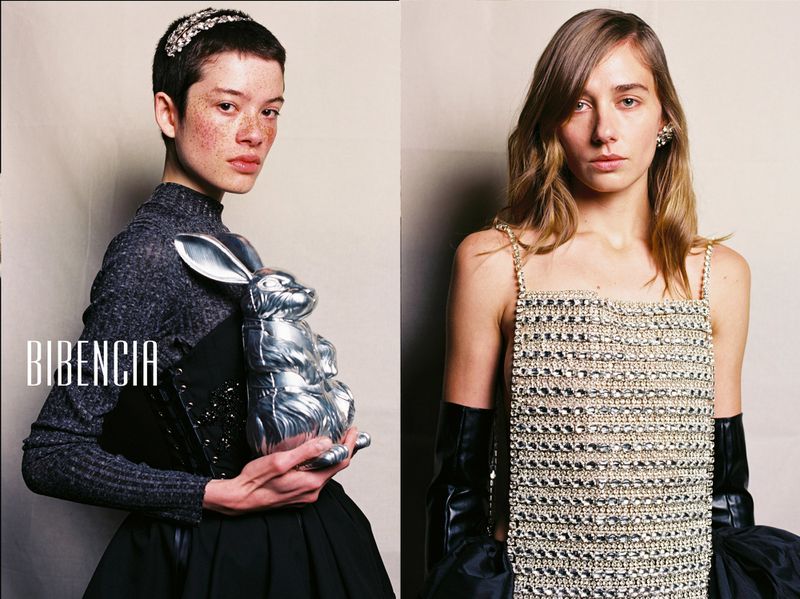 Two models showcasing high fashion with a silver rabbit prop and crystal strap top in a studio setting.