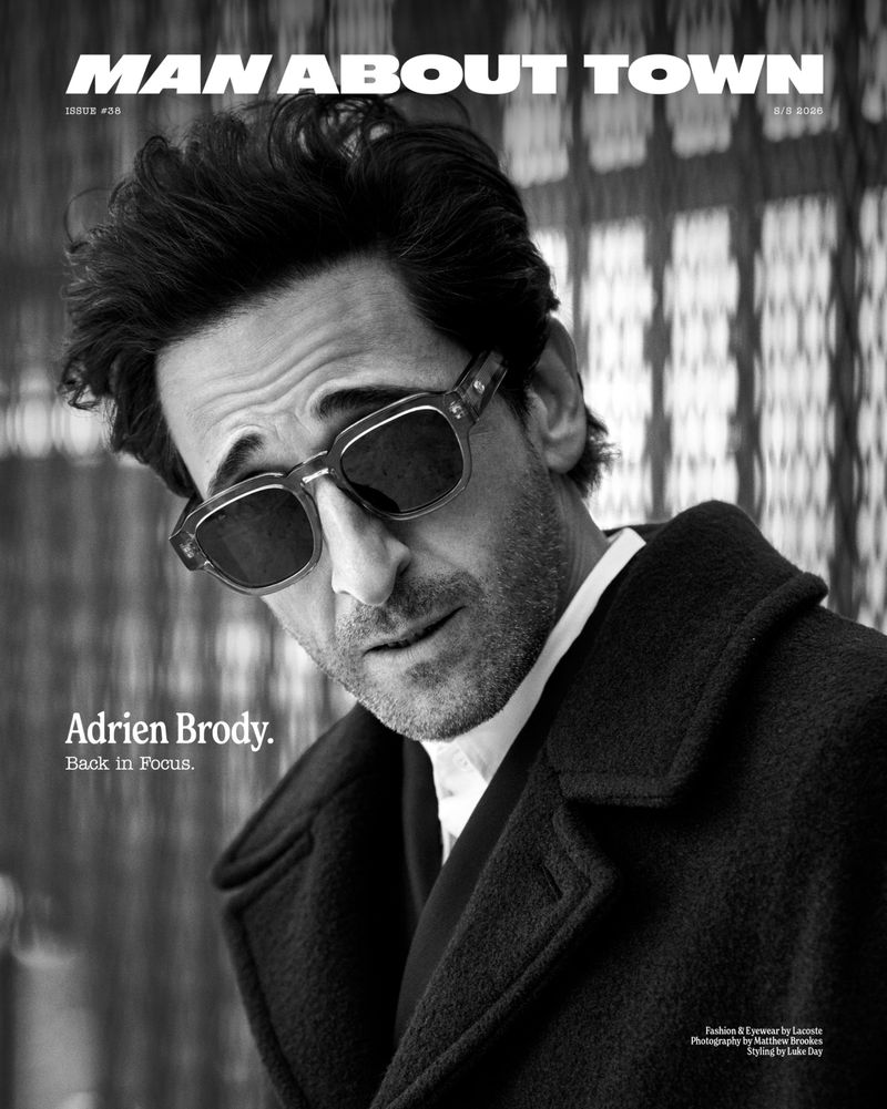 Actor Adrien Brody wearing dark square sunglasses and a black overcoat on the cover of Man About Town magazine.
