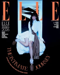 Actress Ninna Yanin seated in a window frame wearing a white dress and draped sash for Elle Vietnam magazine cover.