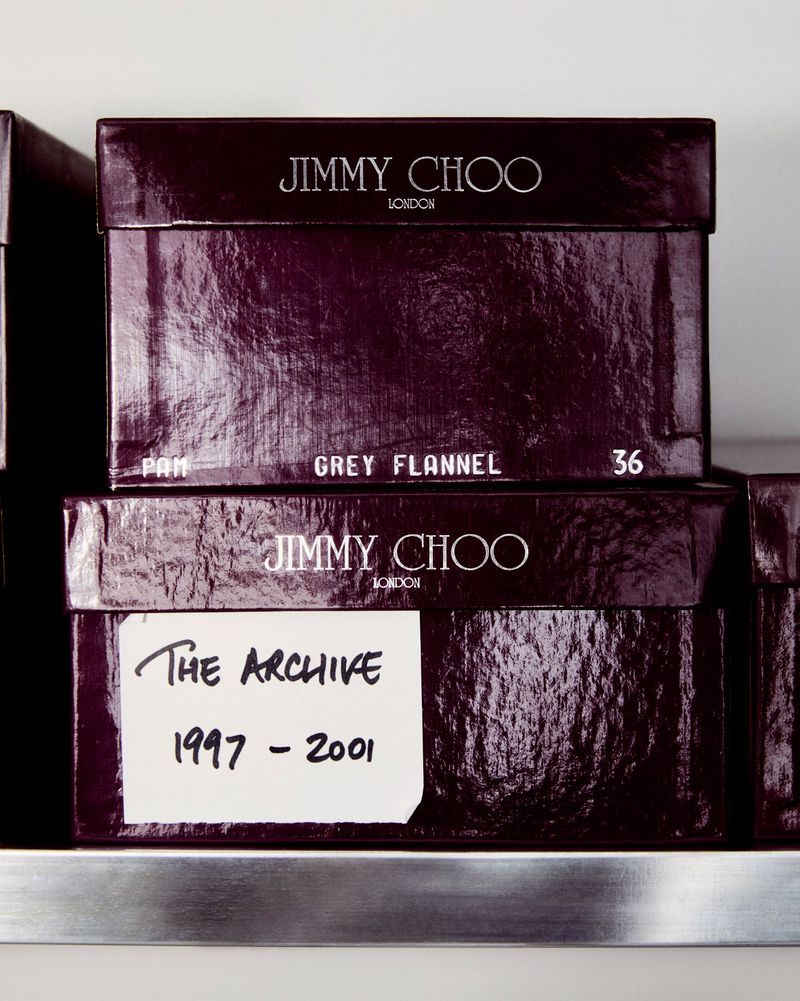Stack of Jimmy Choo shoe boxes in dark purple. The top box reads 'Grey Flannel 36,' with a handwritten label reading 'The Archive.'
