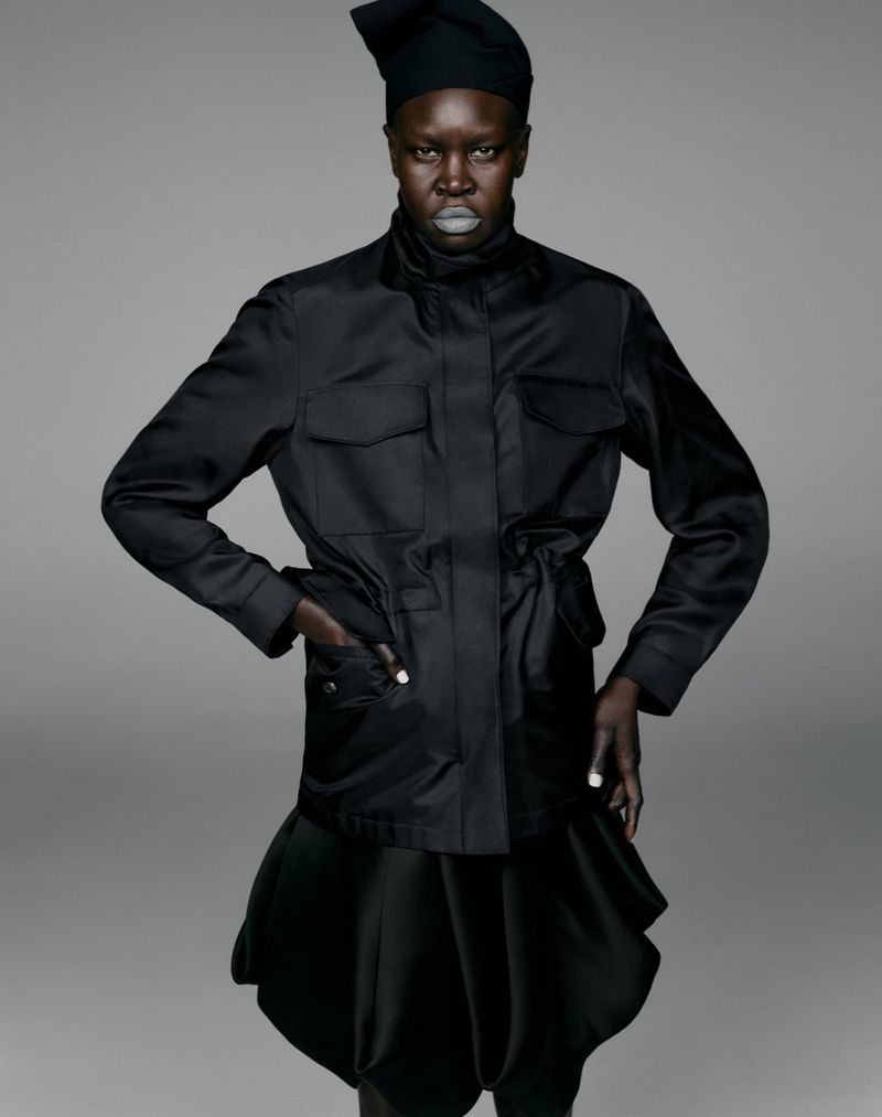 Model Alek Wek wearing a black utility jacket and matching skirt against a seamless grey backdrop for Cap 74024.
