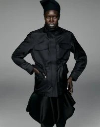 Model Alek Wek wearing a black utility jacket and matching skirt against a seamless grey backdrop for Cap 74024.