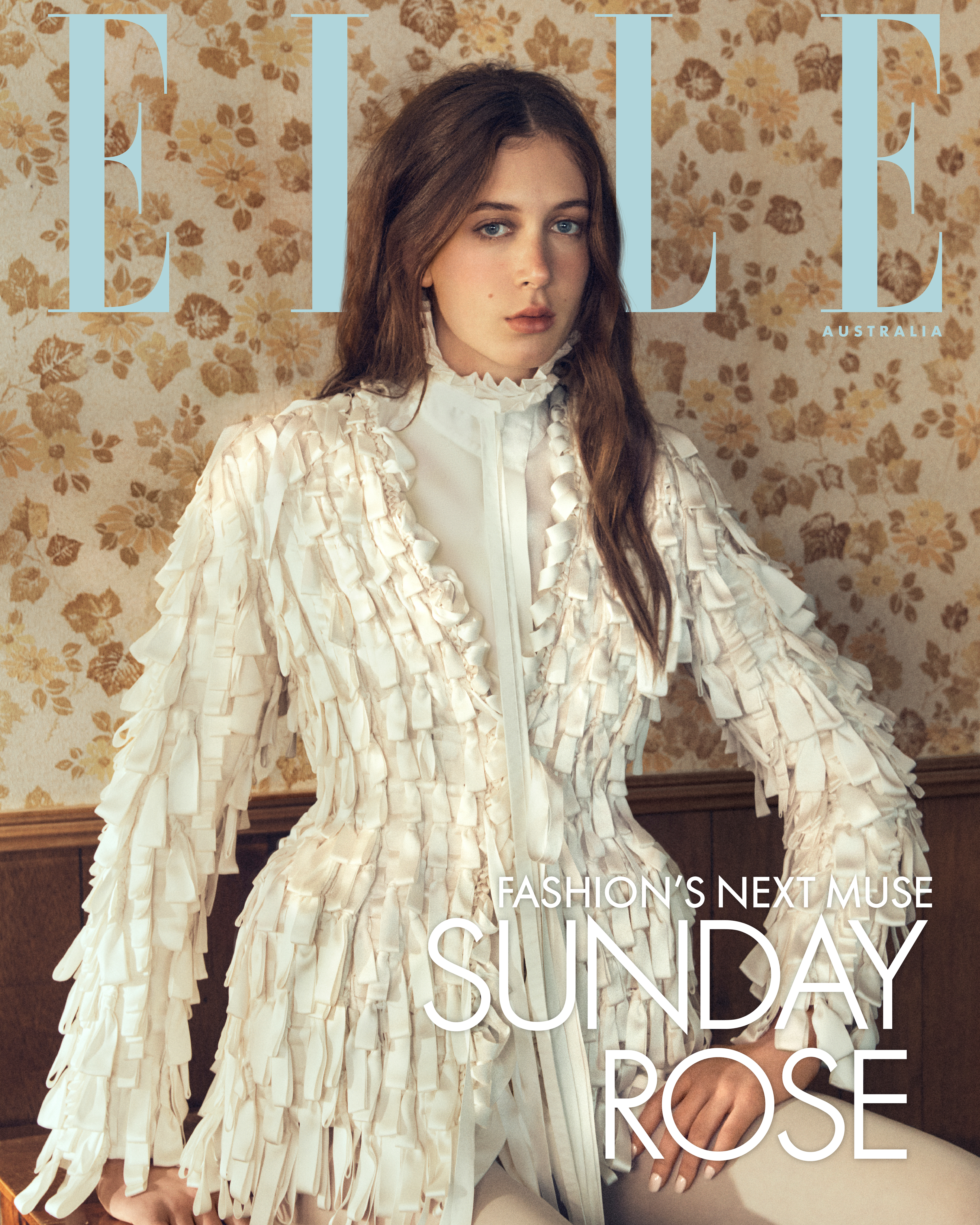 Sunday Rose posing for Elle Australia wearing a textured white fringe jacket against floral wallpaper.