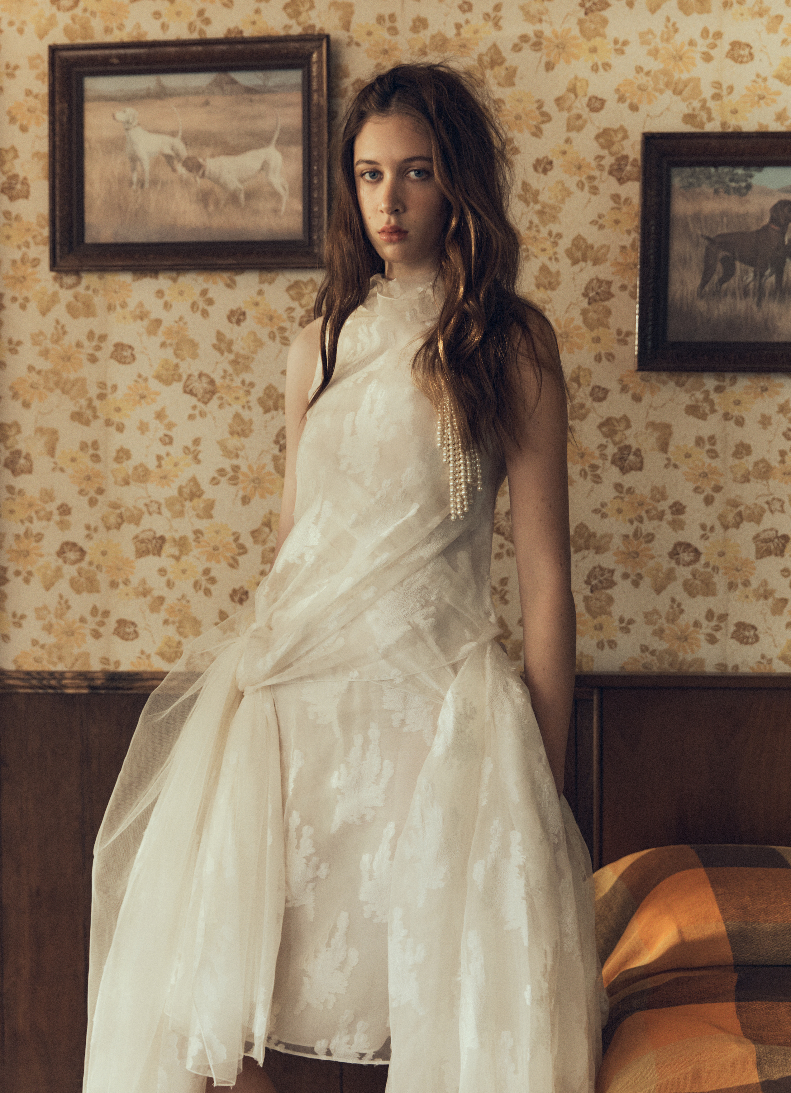 Sunday Rose Kidman Urban poses in a draped cream tulle dress against floral wallpaper in a vintage bedroom setting.