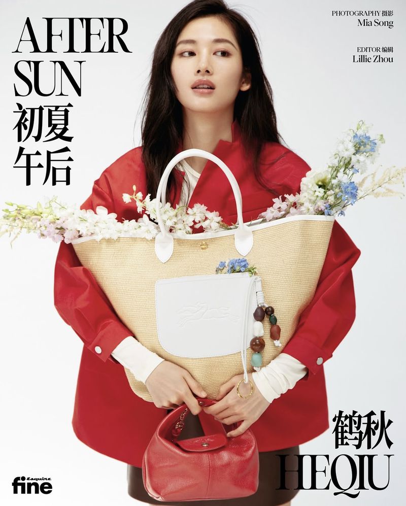 Asian woman in red jacket and straw tote bag with flowers poses indoors for magazine cover; beauty and fashion editorial style.