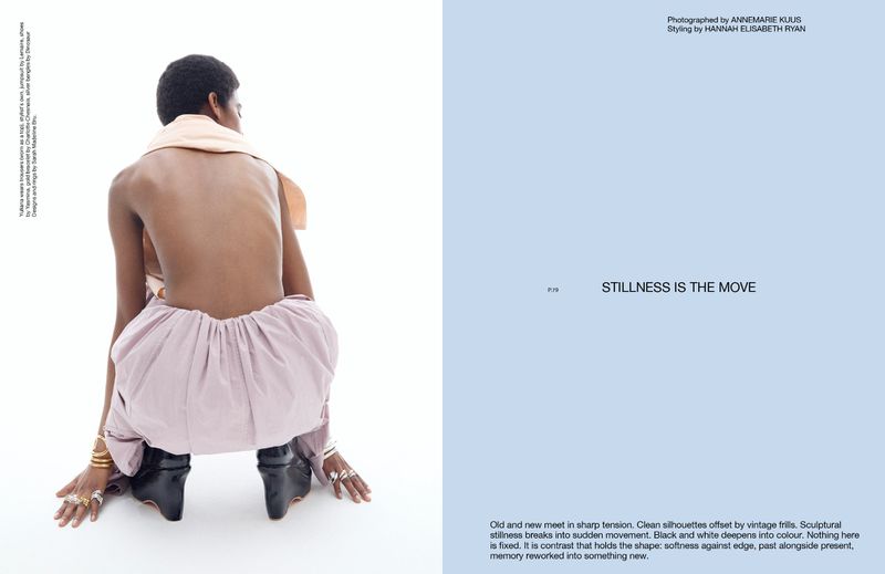 Back view of an adult female squatting with arms forward, wearing a peach-colored scarf, pink pants, and platform boots in a photo studio.