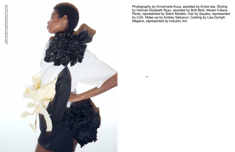 Fashion editorial featuring a Black model in a white top and black skirt, adorned with large black and beige fabric floral embellishments.