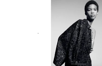 Black and white editorial portrait of a model wearing a textured dark jacket against a light background for endless magazine.