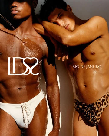Two male models in swimwear, one in white lace-up briefs and one in leopard print, posed under bright directional sunlight.