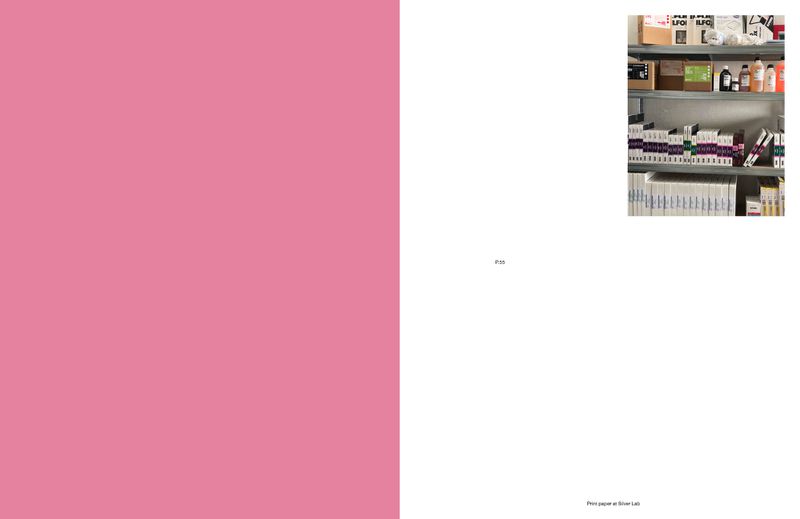 Image of a photo lab storage area. Shelves holding various chemicals, containers, boxes, and paper. A pink wall is on the left side of the image.