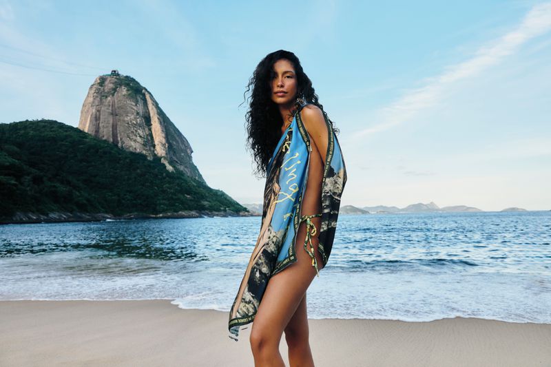 Model posing in a printed blue beach wrap on a sandy shore with Sugarloaf Mountain in the background.
