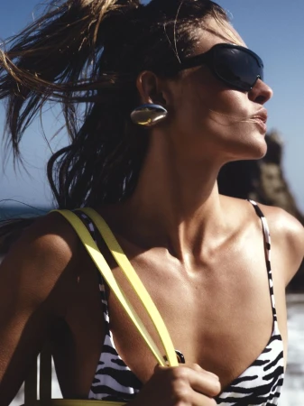 Model Grace Elizabeth wears black wrap sunglasses, a zebra-print bikini top, and a silver earring at the beach.