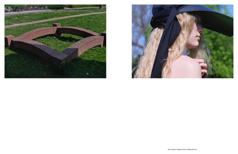 Profile of a blonde woman wearing a large black hat with a ribbon. Brick structure sits on green grass.