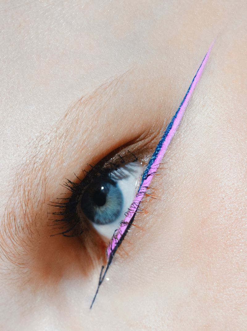 Close-up of a blue eye and bright pink eyeliner with a long, sharp wingtip extending from the outer corner of the eye.