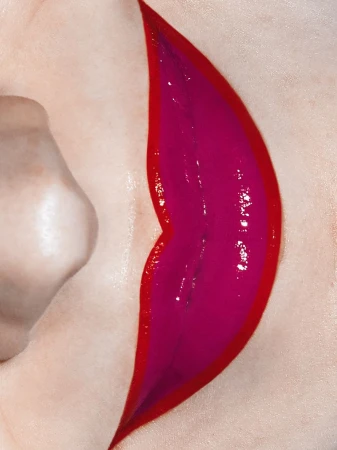 Close-up of a woman's face with glossy magenta lips and a vibrant red lip liner, showcasing beauty and makeup artistry.
