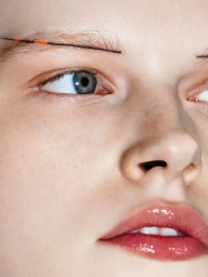 Extreme close-up portrait of model Hannah Motler featuring glossy lips and fine eyebrow makeup for Vogue Ukraine.